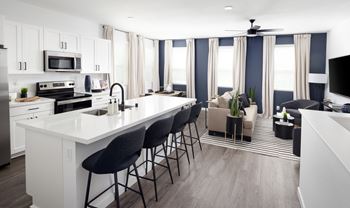 A modern kitchen with white countertops and black bar stools.